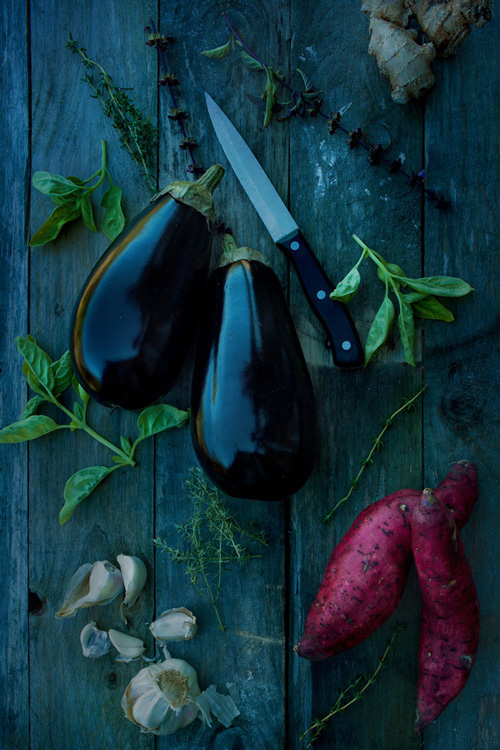Still life of eggplants and kumra with fresh herbs